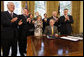 President George W. Bush is applauded after signing H.J. Res. 93, the Renewal of Import Restrictions on Burma and H.R. 3890, the Tom Lantos Block Burmese JADE Act of 2008, Tuesday, July 29, 2008 in the Oval Office of the White House. Applauding President Bush are, from left, Rep. Don Manzullo, R-Ill.; Rep. Chris Smith, R-N.J.; Mrs. Laura Bush, Annette Lantos, widow of Rep. Tom Lantos; Lantos grandson, Shiloh Tillemann; Rep.Rush Holt, D-N.J.; Rep. Joe Pitts, R-Pa.; and Rep. Peter King, R-N.Y. White House photo by Eric Draper