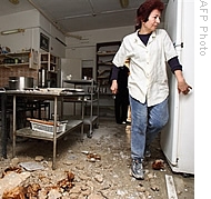 An Israeli woman walks in her damaged kitchen after a rocket fired from southern Lebanon hit the northern Israeli town of Nahariya, 08 Jan 2009