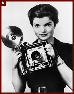 [Jacqueline Kennedy Onassis, née Bouvier, half-length portrait, facing front, holding camera], 1961