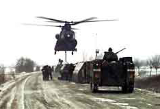 A CH-47 Helicopter from the 159th Aviation Regiment picks up one of the 63 pieces of assault float bridging materials used to construct the float bridge between Croatia and Bosnia, while a Bradley Fighting Vehicle System provides ground security. U.S. Army photo by Sergeant Larry D. Aaron