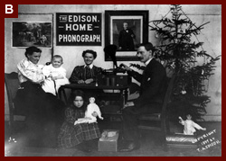 Man, two women and two children listening to phonograph--Girl is holding doll and another doll is under Christmas tree--There is a sign on the wall, The Edison Home Phonograph, and a portrait of Edison. 1897