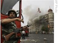 An Indian soldier takes cover as the Taj Mahal hotel in Mumbai burns during a gun battle between the Indian military and militants in November