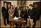 President George W. Bush signs S. 2634, the Garrett Lee Smith Memorial Act, in the Roosevelt Room Thursday, Oct. 21, 2004. The act authorizes the spending of $82 million for youth suicide prevention programs at college campus mental health centers. The legislation is named for Garret Smith, the son of Sen. Gordon Smith, R-Ore., and Sharon Smith, who are standing directly behind the President. Their son committed suicide Sept. 8, 2003. White House photo by Paul Morse