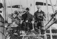 First flight for Katharine Wright, seated in plane with Wilbur; Orville standing to left, in Pau France, 1909