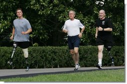 President George W. Bush jogs along the White House jogging track with wounded veterans U.S. Army Sgt. Neil Duncan (Ret.), left, and U.S. Army Specialist Max Ramsey Wednesday, July 25, 2007. White House photo by Chris Greenberg