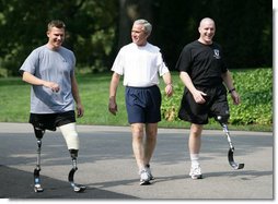 President George W. Bush meets with wounded veterans U.S. Army Sgt. Neil Duncan (Ret.), left, and U.S. Army Specialist Max Ramsey, right, for a jog Wednesday, July 25, 2007 around the South Lawn of the White House. White House photo by Eric Draper