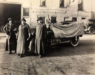 Three women standing in front of a car