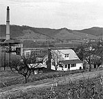 House with a power plant and moutains in the background