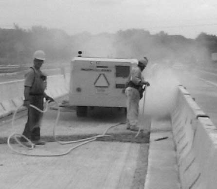 Workers sandblasting a roadway