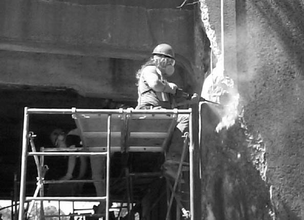 Worker drilling into a rock creating dust