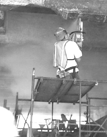 Worker on scaffold using a powertool