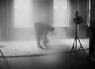 Worker operating a saw in an enclosed, dust-filled room