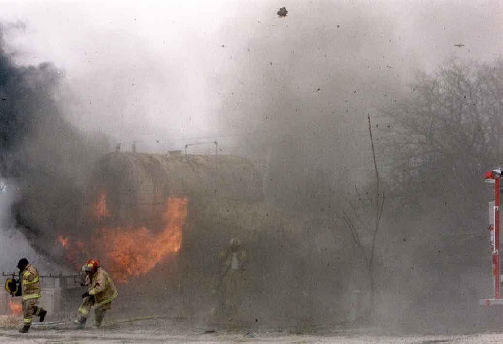 Photo 3: Photograph of Tank #1 burning immediately after the explosion, showing fleeing fire fighters.