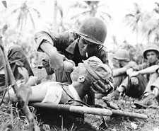 Image: Navy corpsman give drink to wounded marine on Guam