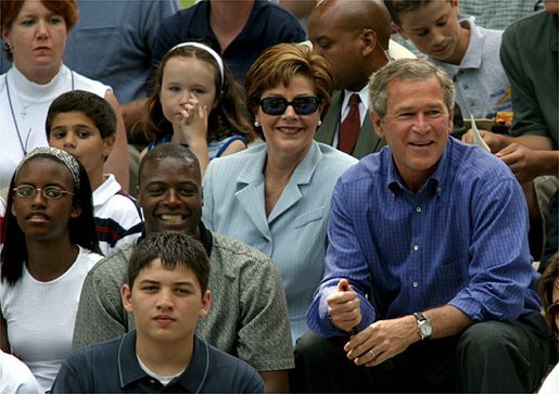 President George W. Bush, Laura Bush and Washington Redskins star Darrell Green (seated in front of Mrs. Bush) watch the tee ball action on the South Lawn Sunday, June 22, 2003. Mr. Green is the Chairman of the President's Council on Service and Civic Participation and during the game recognized Tanisha Faulkner and Mileika Miki of Fort Meade 4-H for their volunteer service. White House photo by Lynden Steele.