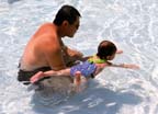 A father teaching his young daughter to swim.