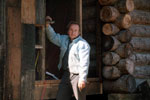 A man standing outside of a log building.