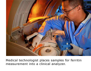 Medical technologist places samples for ferritin measurement into a clinical analyzer.