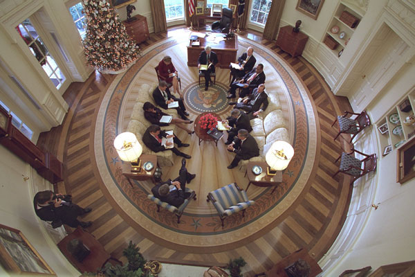 President George W. Bush hosts a meeting in the Oval Office decorated with the new presidential rug on December 20, 2001. The rug, which is unique to the Bush administration, arrived earlier in the week and was unveiled to the media on Friday December 21, 2001. Members from the Office of Homeland Security and other White House staff attended the meeting. The participants included (clockwise from the bottom), President George W. Bush, Governor Tom Ridge, Dr. Condoleezza Rice, Admiral Steve Abbot, Karen Hughes, Dean McGrath, Karl Rove, Albert Hawkins, Mitch Daniels, Josh Bolten, and Andy Card. White House Photographer Paul Morse is at left. White House photo by Paul Morse.