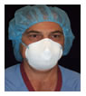 health care worker wearing scrubs, a hair net and a protective half-face mask