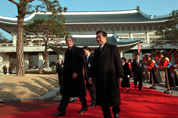 President George W. Bush and President Kim Dae-Jung proceed through an arrival ceremony at The Blue House in Seoul, Republic of Korea, Feb. 20, 2002. 