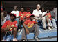 President George W. Bush sits in the stands and watches a tee ball game Wednesday, Feb. 20, 2008, at the Ghana International School in Accra, Ghana. White House photo by Eric Draper