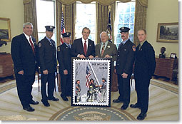 President George W. Bush stands for photos at the unveiling of the Postal Service's new stamp Commemorating the efforts of recovery workers in the aftermath from the attack upon the World Trade Center, President George W. Bush unveils a new stamp in the Oval Office March 11, 2002. Standing with the President from left to right are Postmaster General Jack Potter, Firefighter Bill Eisengrein, Firefighter George Johnson, Congressman Gary Ackerman, Firefighter Dan Williams and Photographer Thomas E. Franklin. White House photo by Tina Hager.