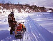 A snowmobiler takes a break from riding on frozen Birch Creek.