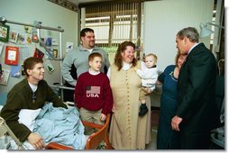 President George W. Bush embraces the mother-in-law of U.S. Army Staff Sergeant Roy Mitchell, who is at left, as other family members look on during the President’s visit to Walter Reed Army Medical Center in Washinton, D.C., Thursday, December 18, 2003. President Bush had just presented Sgt. Mitchell The Purple Heart for injuries sustained while serving in Iraq. Sgt. Mitchell is from Milan, Indiana. Others present are, from left, Jerry Stoneking, Zachary Bice and Sgt. Mitchell's wife, Michelle, who is holding their son Jerrett.  White House photo by Eric Draper