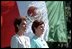 As a breeze unfurls the two nation's flags, Laura Bush and Martha Sahagun de Fox stand at attention.