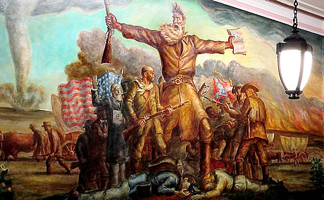 Detail of a mural. A white-bearded man in buckskins stands with outstretched arms, a rifle in his right hand and a scroll in his left hand. Behind him a mixed crowd of people stand, holding a U.S. flag and a Confederate flag. Behind the crowd, a tornado roils.