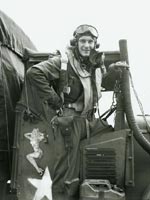 Keller stands on a truck wearing full flight gear, smoking a cigarette.