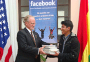 Charge d'Affaires James Creagan hands the set of books to student Israel Mamani