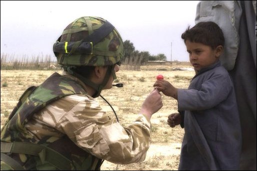 An RAF Regiment gunner shares sweets with an Iraqi child.