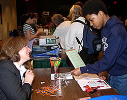 Library staff person smiling as a student  uses materials for an experiment.