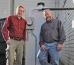 FRIES WITH THAT: James Peret, left, president of Boylston-based Owl Power Co., maker of the Vegawatt system, shows George Carey, owner of Finz, how his Dedham eatery is saving electricity costs by reusing its frying oil.