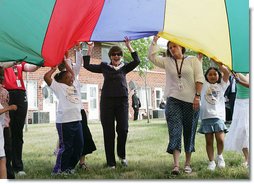 Mrs. Laura Bush participates in playing with a colorful parachute with children and staff outside the Meadowbrook Collaborative Community Center, Tuesday, June 6, 2006 in St. Louis Park. Minn.  White House photo by Shealah Craighead