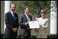 Mrs. Laura Bush presents a plaque to John McLaughlin, center, president and CEO of the USS Midway Museum in San Diego, Calif., and Scott McGaugh, marketing director of the museum, honoring them with a 2007 Preserve America Presidential Award in the Rose Garden at the White House Wednesday, May 9, 2007. White House photo by Joyce Boghosian