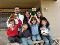 [Photo: The Brewer family smile proudly in front of their new home]