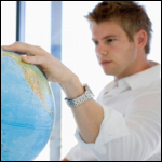 Photo: A young man looking at a globe