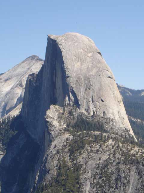 The picture shows Half Dome, a large rounded mountain sparsely populated with trees, at Yosemite National Park, California.