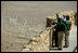 President George W. Bush and Mrs. Laura Bush and Prime Minister Ehud Olmert of Israel and Mrs. Aliza Olmert stand on the upper level of Masada, a palatial fortress built by King Herod, and listen to Eitan Campbell, Director of Masada National Park during their visit to the historic site Thursday, May 15, 2008. On the fringe of the Judean Desert near the shore of the Dead Sea, the camps, fortifications and assault ramp at its base constitute the most complete surviving ancient Roman siege system in the world.