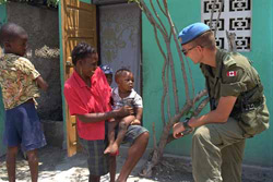 A Canadian peace-keeping soldier from UNSMIH talking with a local mother and her children during his patrol of the streets of Port-au-Prince.