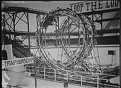Photo: old wooden roller coaster  with two loops.  Signs say, "Loop the Loop," and "Strap yourselves."