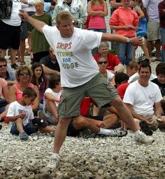 Photo: a man winding up to throw a stone.