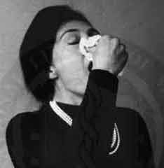 Photo: woman holding a handkerchief to her nose, mouth open.