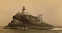 Photo of a lighthouse on  small rocky island.
