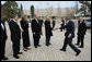 With Prime Minister Ehud Olmert looking on, President George W. Bush reaches out to Israel's President Shimon Peres Friday, Jan. 11, 2008, as he arrives at Yad Vashem , the Holocaust Museum, in Jerusalem. White House photo by Eric Draper