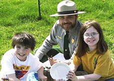 Image of a park ranger with two children learning about archeology