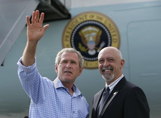 President George W. Bush waves to the family of USA Freedom Corps Greeter Paul Freeman in front of Air Force One at Manchester Airport, Friday, Oct. 1, 2004. Freeman has volunteered for the past eight years with the Greater Manchester Chapter of the American Red Cross. Freeman is a member of the emergency response team recently deployed to assist with relief efforts in the aftermath of hurricanes Frances and Ivan. White House photo by Eric Draper.